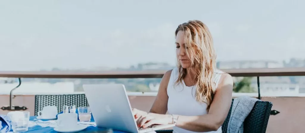 Woman using laptop for online valuation next to man inspecting a house in-person for valuation.